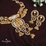 The jewelry set consists of a kemp stone-studded heavy choker along with fine temple gold polish and a pair of matching dangler earrings. necklace secured with drop-down closure and earrings secured with the post and back closure.